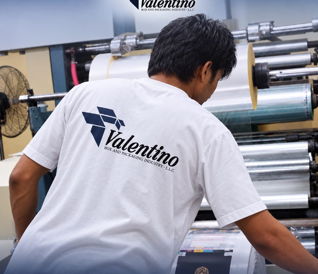 Machine operator at a printing press feeding printed film reels on the production floor